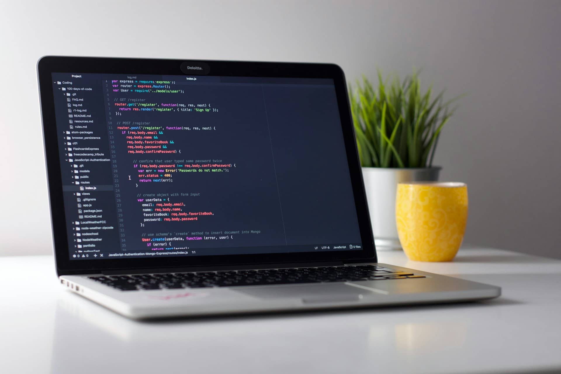 Developer laptop with glowing code on screen in a dark workspace